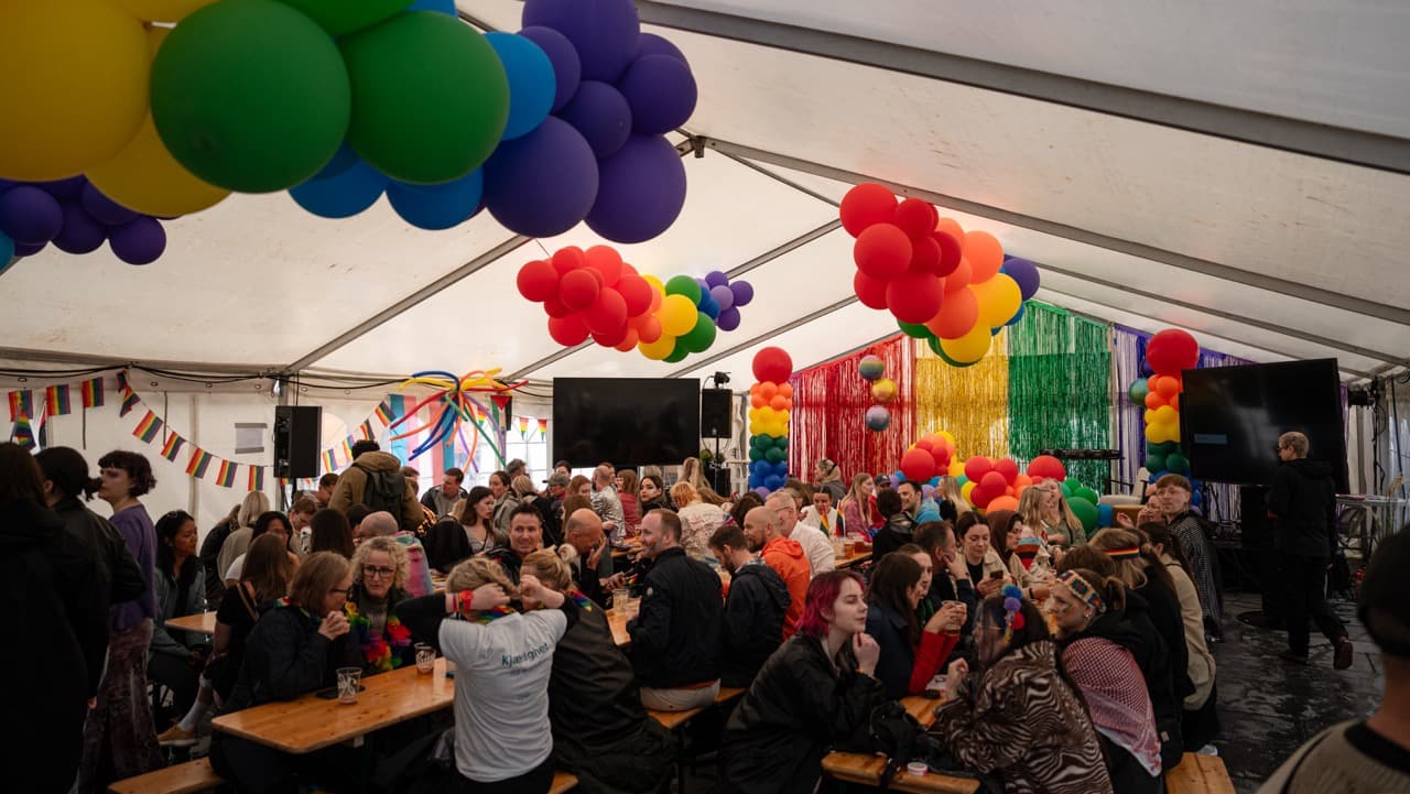 Stort rammetelt og bord og benkesett under pride feiring